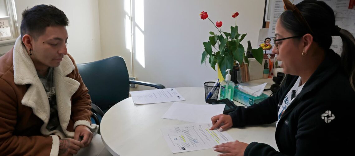 Reina Lara (right), coordinator of operations for NeighborHealth’s patient services department, helped Alexander Amaya of Chelsea with a health insurance application Monday.